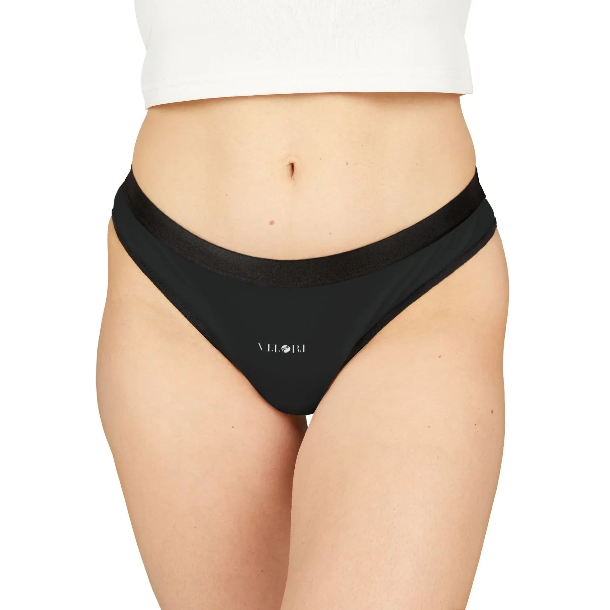 Close-up of a woman wearing black VILORI branded bikini bottoms and a white cropped top