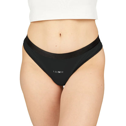 Close-up of a woman wearing black VILORI branded bikini bottoms and a white cropped top