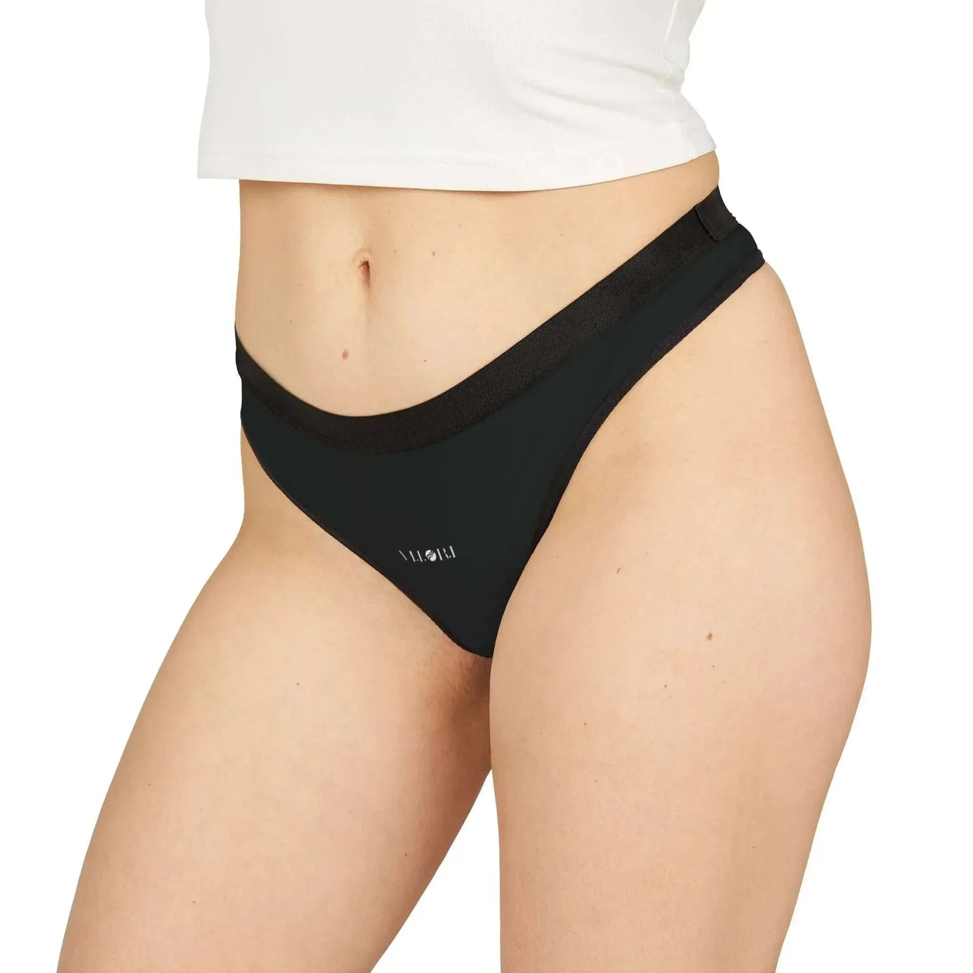 Close-up of woman wearing black bikini bottoms with white crop top on white background